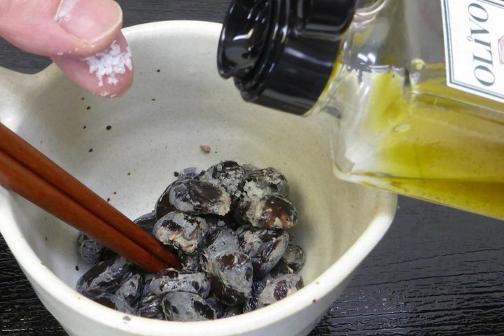 黒豆の納豆に塩をひとつまみ、オリーブオイルをかけるところ